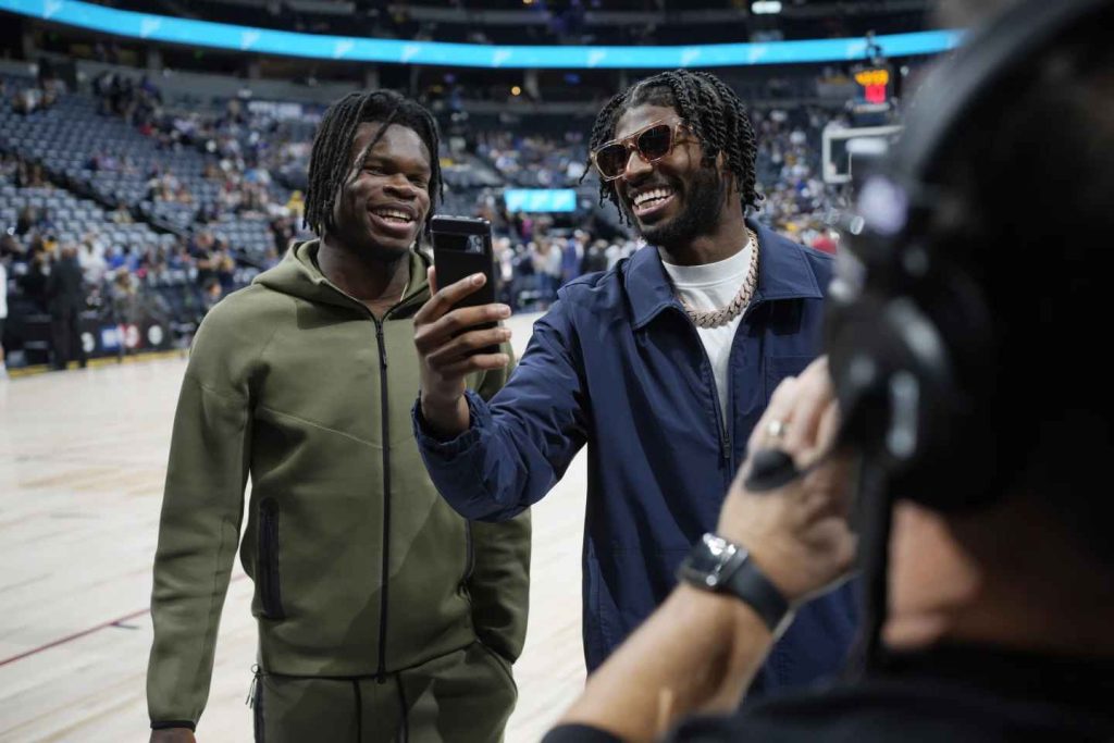 Colorado wide receiver Travis Hunter, left, and quarterback Shedeur Sanders laugh before the Denver Nuggets' NBA basketball game against the Los Angeles Lakers on Tuesday, Oct. 24, 2023, in Denver. (Photo by David Zalubowski)